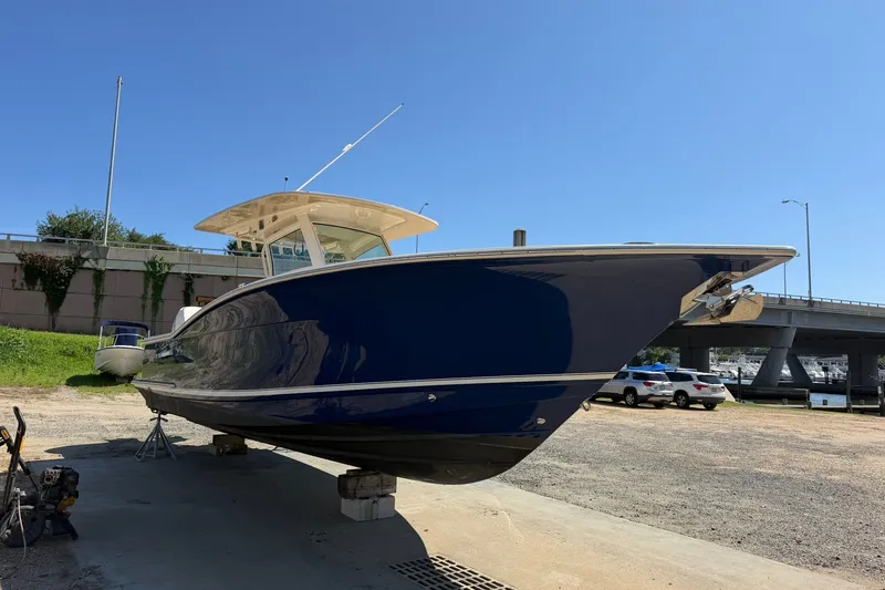 Slide: The Image of 2019 Scout 300 LXF boat on dry dock, blue hull, sunny day. - 2