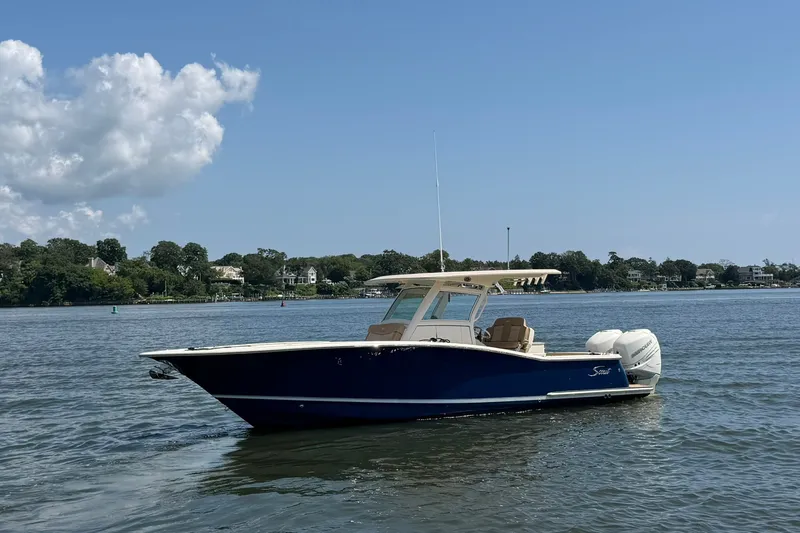 Slide: The Image of 2019 Scout 300 LXF boat on calm water with scenic shoreline background. - 1