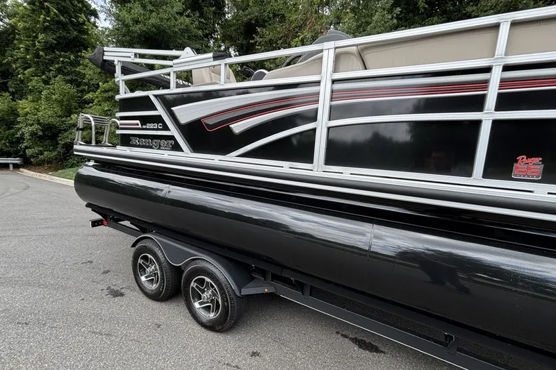 Slide: The Image of 2023 Ranger 223C pontoon boat on trailer, black with red accents, parked on road. - 19