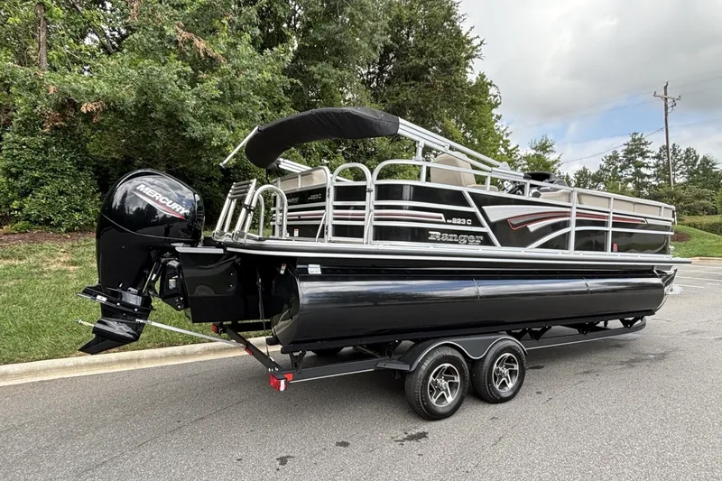 Slide: The Image of 2023 Ranger 223C pontoon boat with Mercury outboard engine on a trailer, parked outdoors. - 15