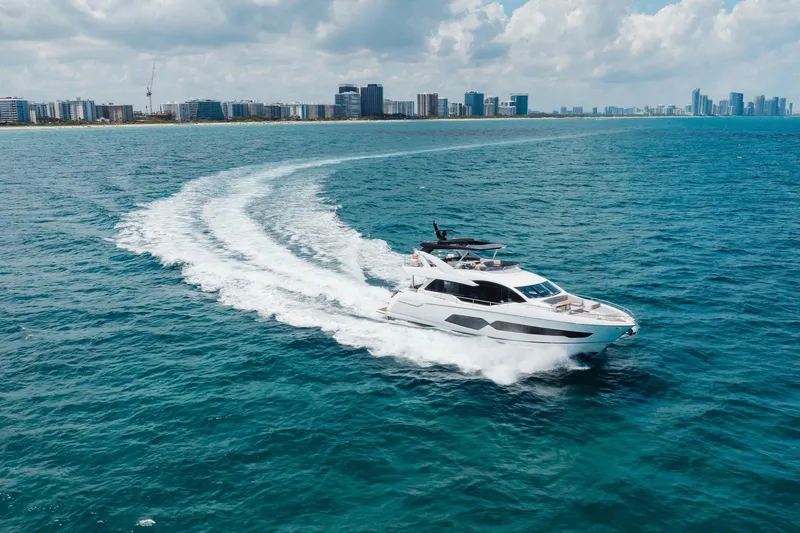 Slide: The Image of Sunseeker 76 Yacht 2022 cruising on ocean near city skyline under cloudy sky. - 23
