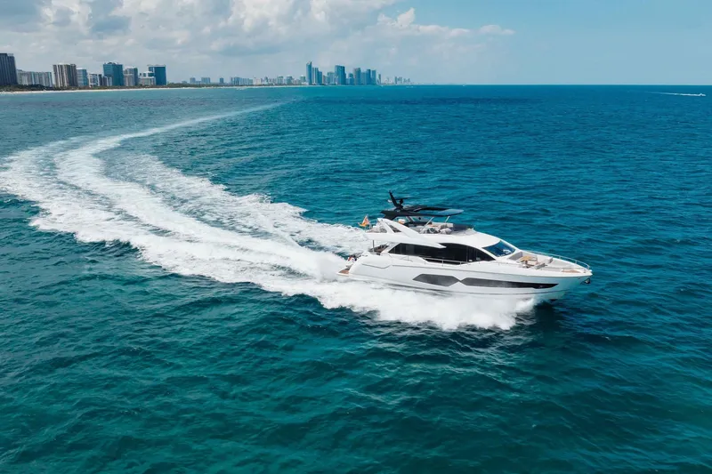 Slide: The Image of Sunseeker 76 Yacht 2022 cruising on blue ocean near city skyline. - 22
