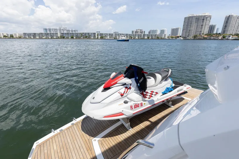 Slide: The Image of Jet ski on Sunseeker 76 Yacht's deck, 2022 model, with city skyline in background. - 88
