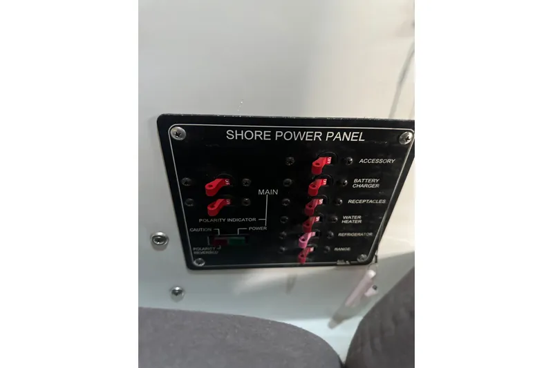Slide: The Image of Shore power panel on 1999 Skagit Orca 24 boat, featuring various switches and indicators. - 28