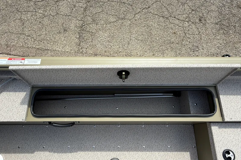 Slide: The Image of 2026 Lund 1875 Alaskan SS boat storage compartment with textured interior and safety labels. - 23