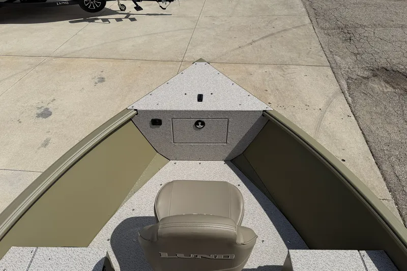 Slide: The Image of 2026 Lund 1875 Alaskan SS boat interior with seating and storage, parked on concrete. - 10