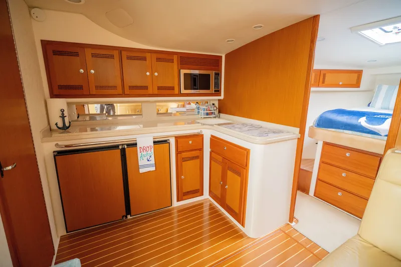 Slide: The Image of 2005 Cabo 40 Express yacht interior with wooden cabinetry, kitchenette, and cozy sleeping area. - 16