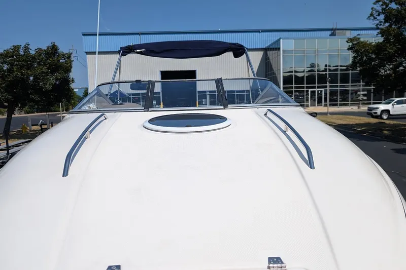 Slide: The Image of 2002 Regal 2450 LSC boat with sleek design, parked near a modern building. - 10