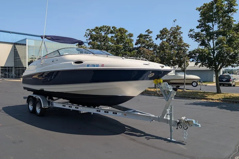 Slide: The Image of 2002 Regal 2450 LSC boat on trailer, parked outdoors near trees and buildings. - 6