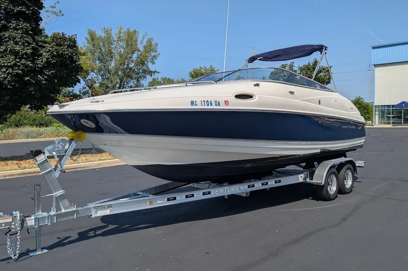 The Image of 2002 Regal 2450 LSC boat on trailer, parked outdoors, with blue and white exterior. - 0
