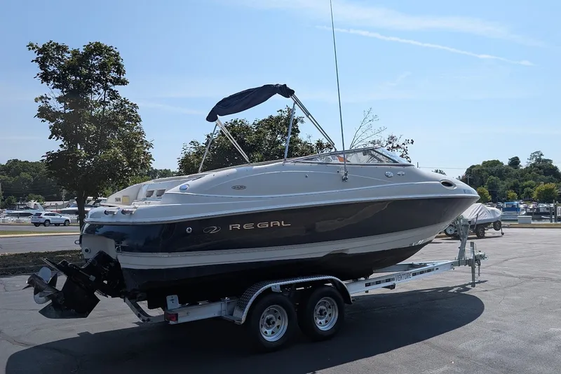 Slide: The Image of 2002 Regal 2450 LSC boat on trailer, parked outdoors under clear sky. - 4