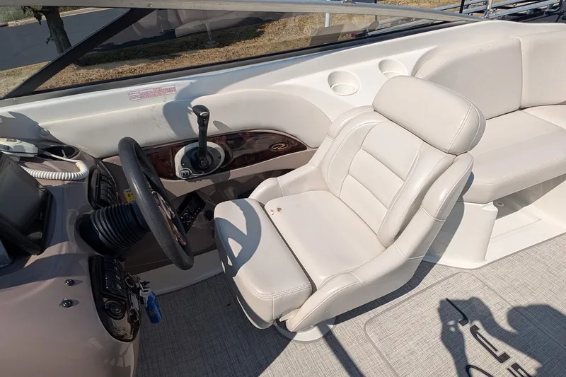 Slide: The Image of Interior of a 2002 Regal 2450 LSC boat featuring steering wheel and white seating. - 31