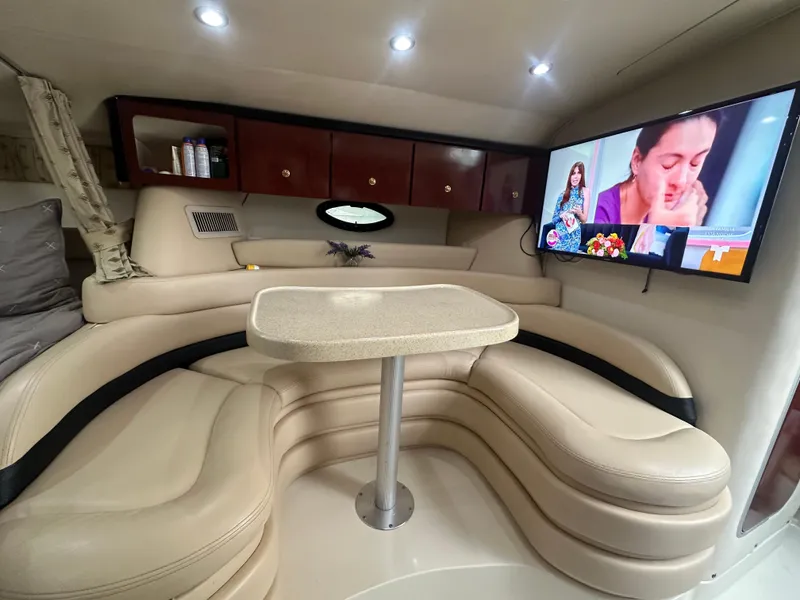 Slide: The Image of 2001 Wellcraft 3300 Martinique yacht interior with beige seating, table, and mounted TV. - 21
