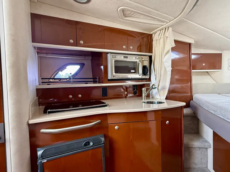 Slide: The Image of The interior of a 2009 Sea Ray Sundancer 310 features a compact kitchen with a microwave and sink. - 15