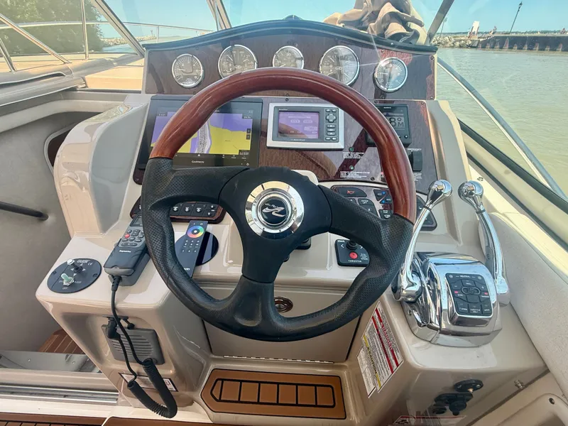 Slide: The Image of The image shows the helm of a 2009 Sea Ray Sundancer 310 with a wooden steering wheel and navigation systems. - 9