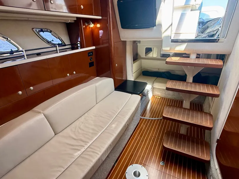 Slide: The Image of Interior of a 2009 Sea Ray Sundancer 310 with cream sofa and wooden steps. - 14