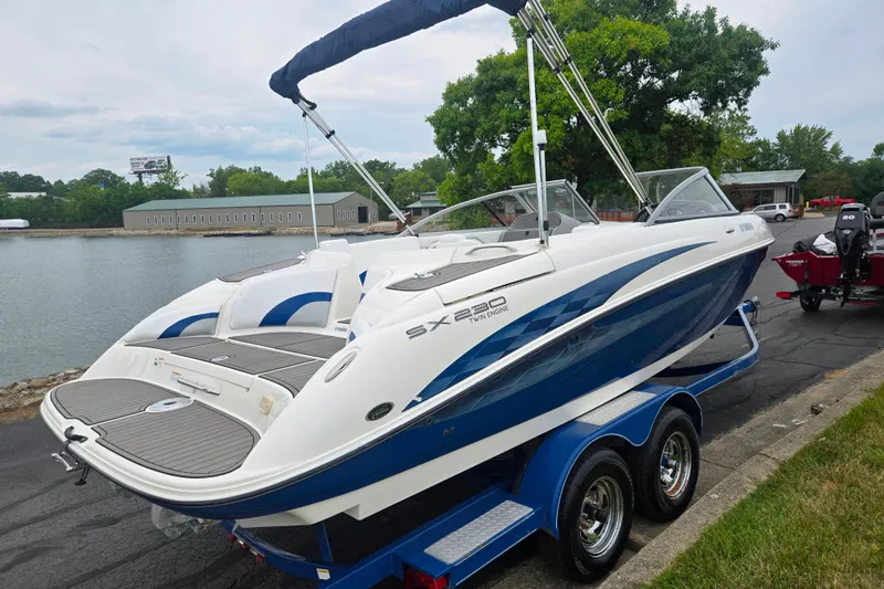 Slide: The Image of 2005 Yamaha Boats SX230 on trailer by lakeside, featuring sleek design and twin engines. - 1