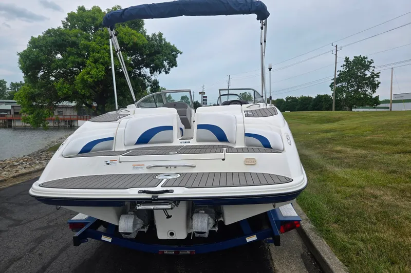Slide: The Image of 2005 Yamaha Boats SX230 on trailer, rear view, near water and grassy area. - 2