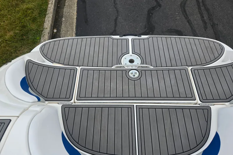 Slide: The Image of 2005 Yamaha Boats SX230 swim platform with gray decking, parked on pavement. - 23