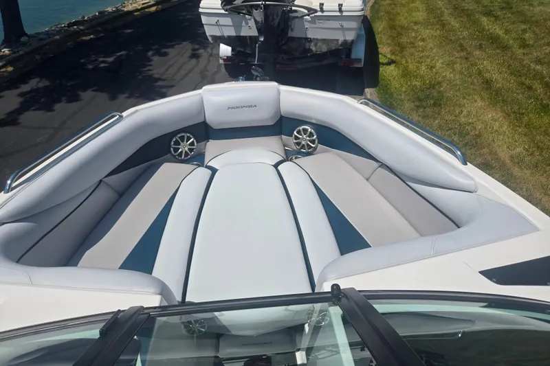 Slide: The Image of 2012 Moomba Mojo 2.5 boat interior with sleek seating and speakers, parked near water. - 16