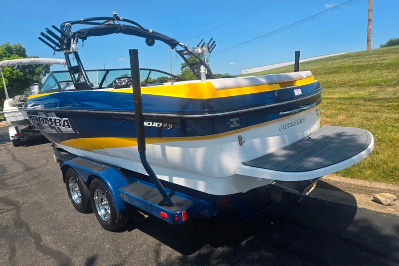 Slide: The Image of 2012 Moomba Mojo 2.5 boat on trailer, blue and yellow design, parked outdoors. - 3