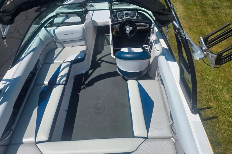 Slide: The Image of 2012 Moomba Mojo 2.5 boat interior with seating and steering wheel, parked on grass. - 11