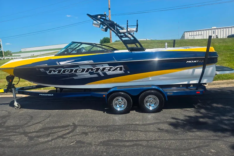 Slide: The Image of 2012 Moomba Mojo 2.5 boat on trailer, blue and yellow design, parked outdoors. - 4