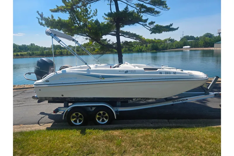 Slide: The Image of 2013 Hurricane SunDeck Sport 188 OB boat on trailer by a lake. - 9