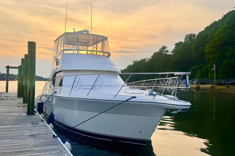 Slide: The Image of 2009 Riviera 45 Open Flybridge yacht docked at sunset, surrounded by serene water and lush greenery. - 4