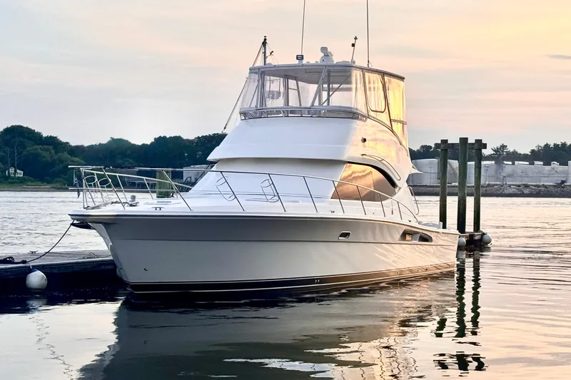 Slide: The Image of 2009 Riviera 45 Open Flybridge yacht docked at sunset, reflecting on calm water. - 1