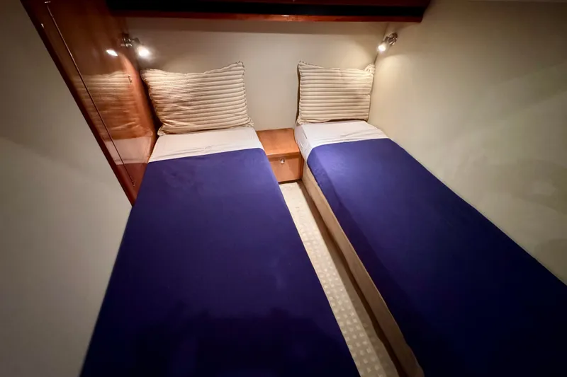 Slide: The Image of Twin beds in a 2009 Riviera 45 Open Flybridge cabin, featuring blue bedding and striped pillows. - 45