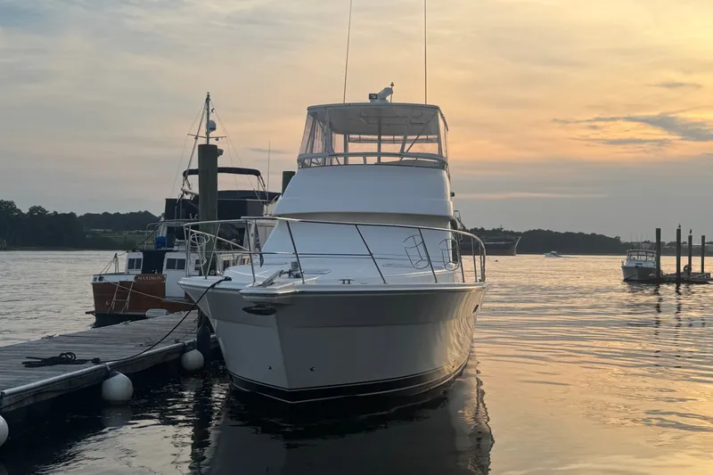 Slide: The Image of 2009 Riviera 45 Open Flybridge yacht docked at sunset, serene waterfront view. - 2