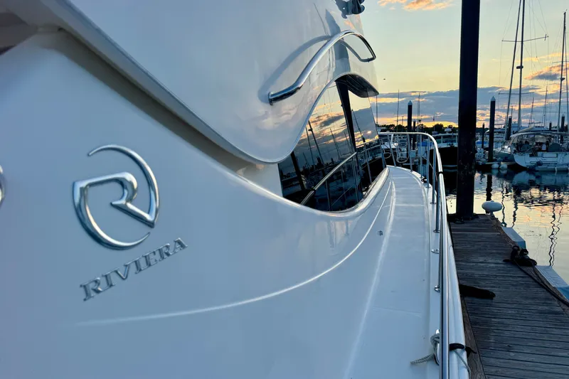 Slide: The Image of 2009 Riviera 45 Open Flybridge yacht docked at sunset, showcasing sleek design and logo. - 8