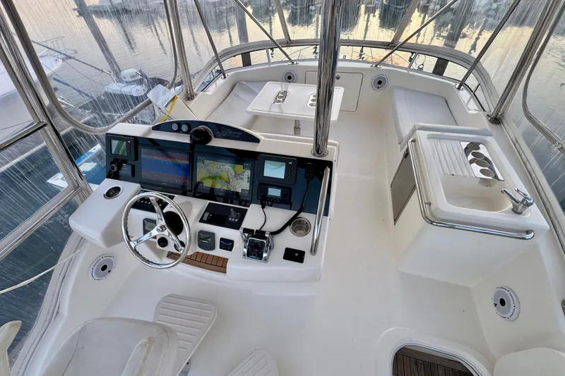 Slide: The Image of 2009 Riviera 45 Open Flybridge helm with navigation screens and controls, docked at marina. - 21