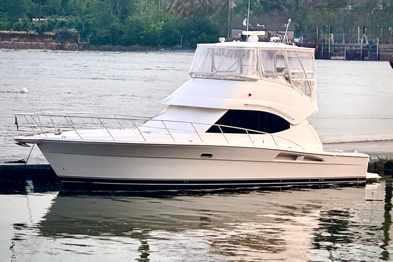 The Image of 2009 Riviera 45 Open Flybridge yacht docked on a serene river. - 0