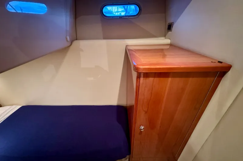 Slide: The Image of Interior cabin of 2009 Riviera 45 Open Flybridge with wooden cabinet and blue bedding. - 46
