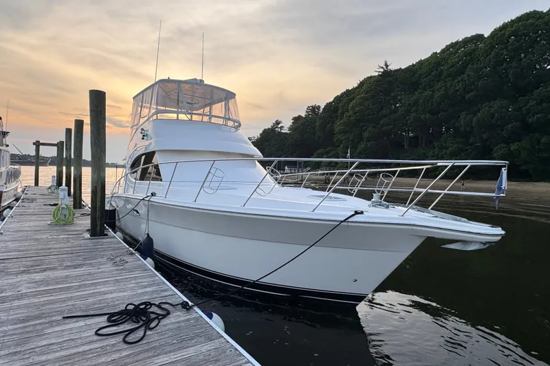 Slide: The Image of 2009 Riviera 45 Open Flybridge yacht docked at sunset, surrounded by serene water and lush trees. - 3