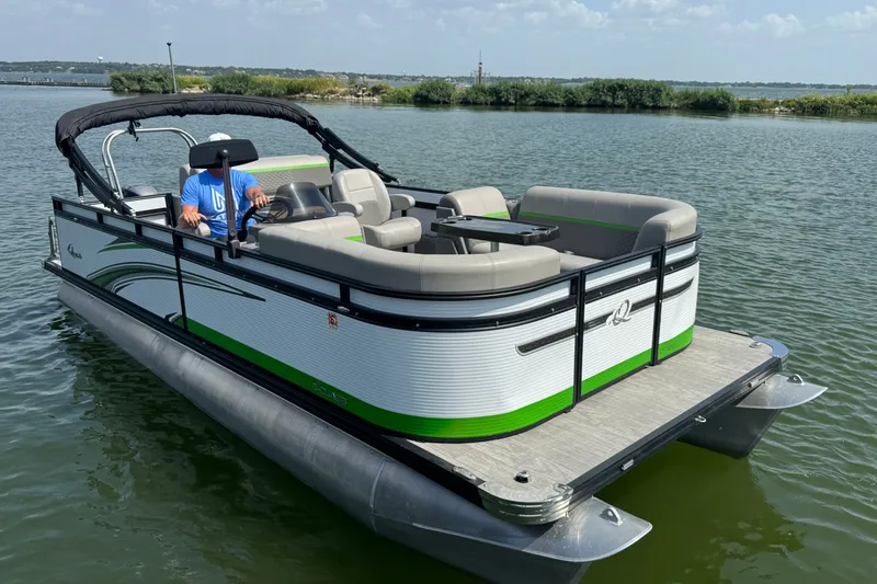 Slide: The Image of 2023 Qwest Lanai 820 pontoon boat on a serene lake. - 1