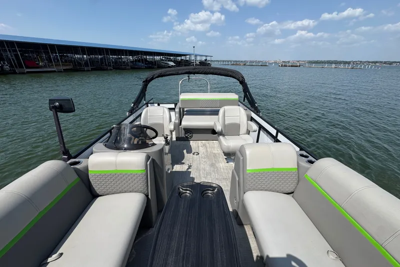 Slide: The Image of 2023 Qwest Lanai 820 pontoon boat interior with seating, on a sunny lake. - 7