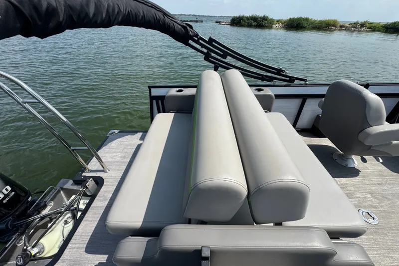 Slide: The Image of 2023 Qwest Lanai 820 pontoon boat with gray seating, on a calm lake. - 16
