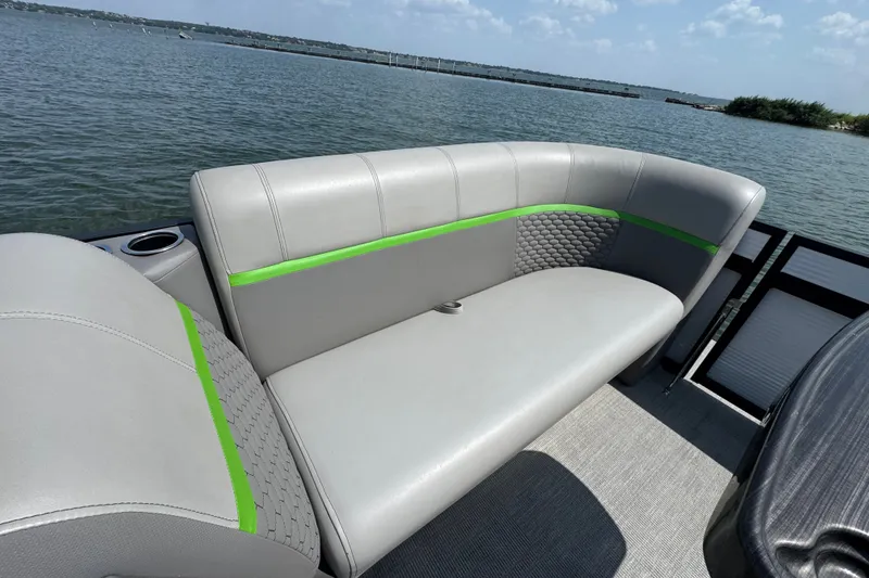 Slide: The Image of 2023 Qwest Lanai 820 boat interior with gray seating and green accents on a sunny day. - 6
