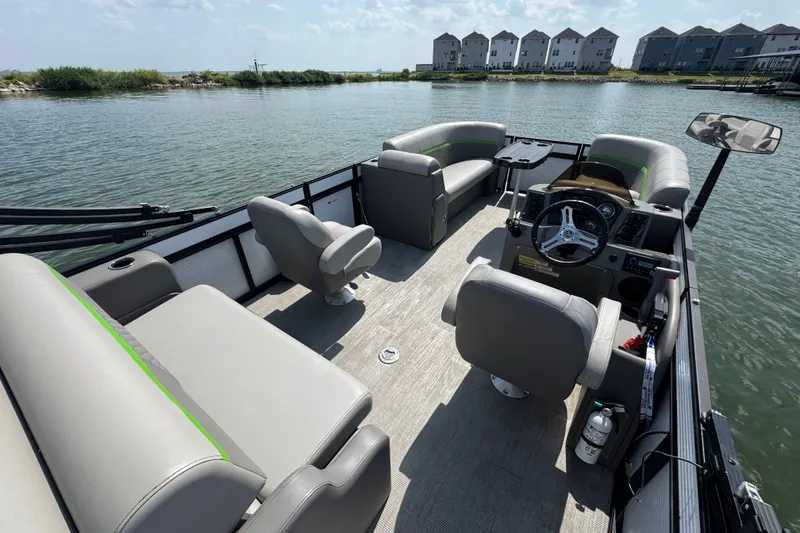 Slide: The Image of 2023 Qwest Lanai 820 pontoon boat interior with plush seating and steering console on a calm lake. - 19