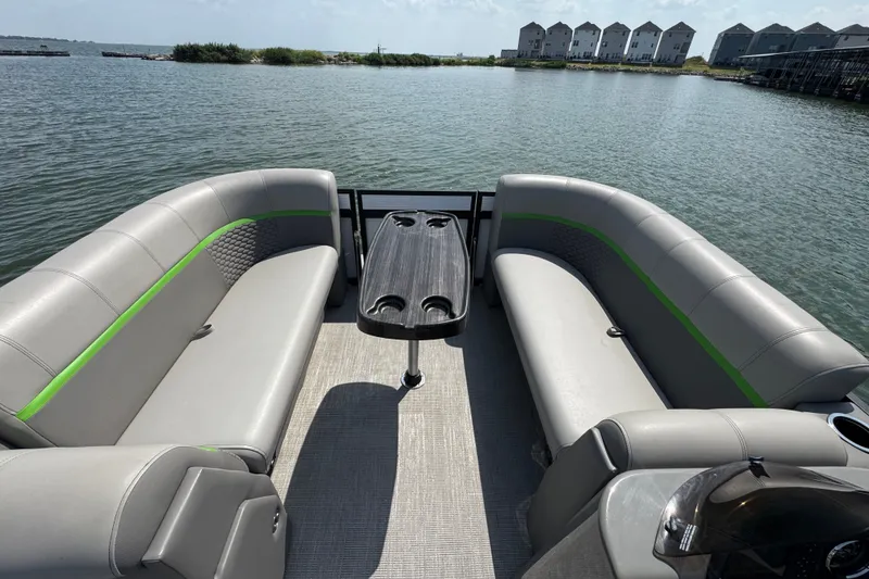 Slide: The Image of 2023 Qwest Lanai 820 pontoon boat interior with gray seating and a central table on a lake. - 4