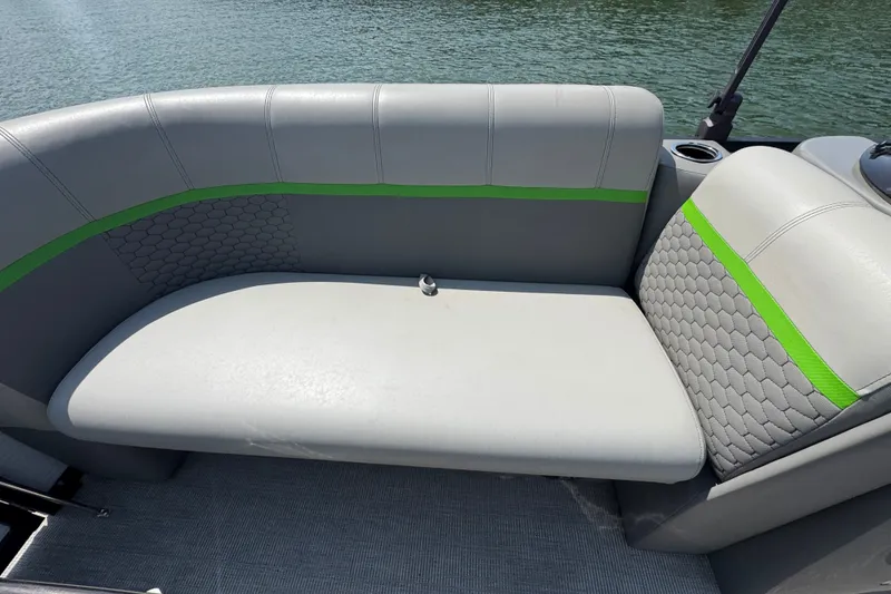 Slide: The Image of 2023 Qwest Lanai 820 boat interior with gray and green cushioned seating by the water. - 5
