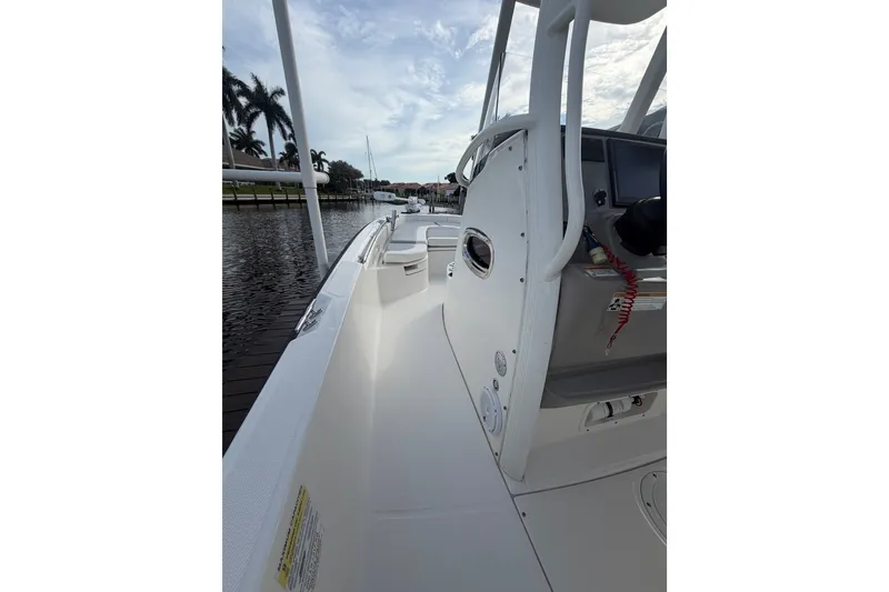 Slide: The Image of 2016 Boston Whaler 240 Dauntless boat interior, docked by palm trees under a cloudy sky. - 14