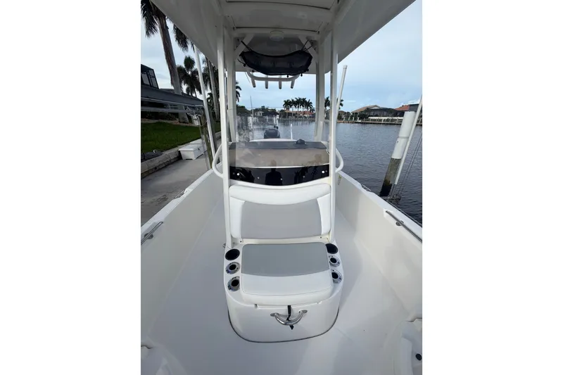 Slide: The Image of 2016 Boston Whaler 240 Dauntless boat interior with seating and console, docked by waterfront homes. - 10