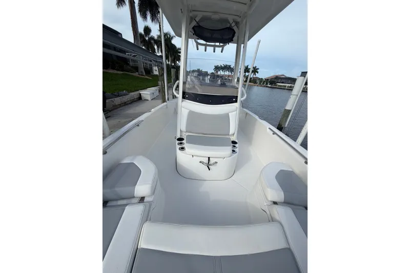 Slide: The Image of 2016 Boston Whaler 240 Dauntless boat interior with seating and console, docked by waterfront. - 8