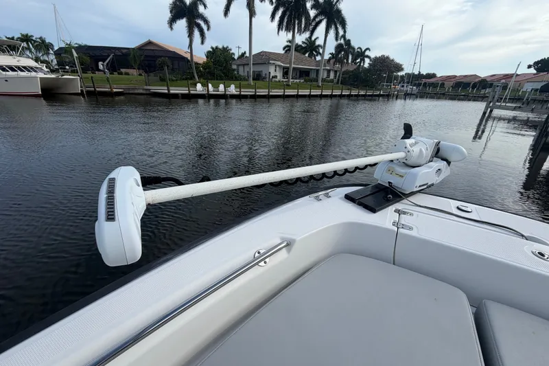 Slide: The Image of 2016 Boston Whaler 240 Dauntless boat with trolling motor, docked by waterfront homes. - 28