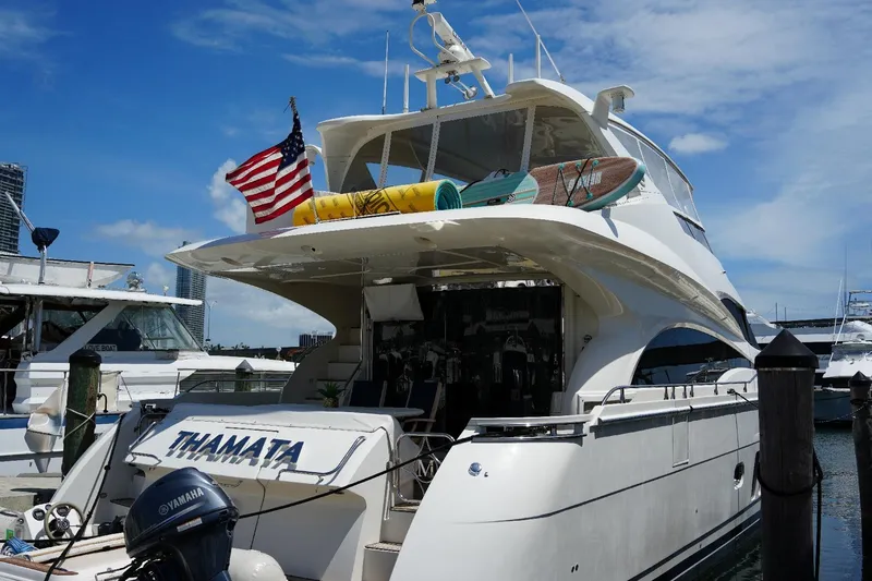 Slide: The Image of Luxury 2008 Marquis 65 Skylounge yacht docked, featuring American flag and surfboards on deck. - 2