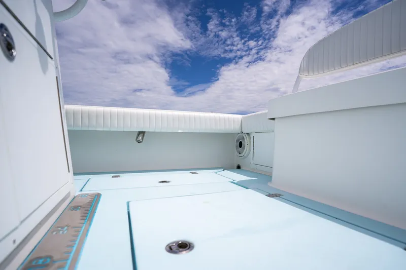 Slide: The Image of 2018 Dorado 25 SE boat interior with blue deck and white seating under a cloudy sky. - 58